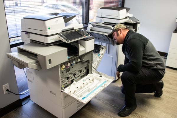 A on-site copier repair technician examining a copier machine.